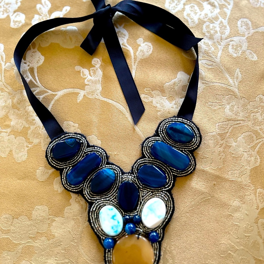 Chico’s necklace with many large stones and tied with a navy ribbon.